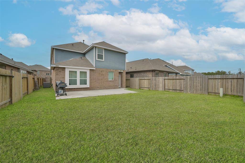 Spacious backyard with a well-maintained lawn & a concrete patio area ideal for outdoor activities & entertaining