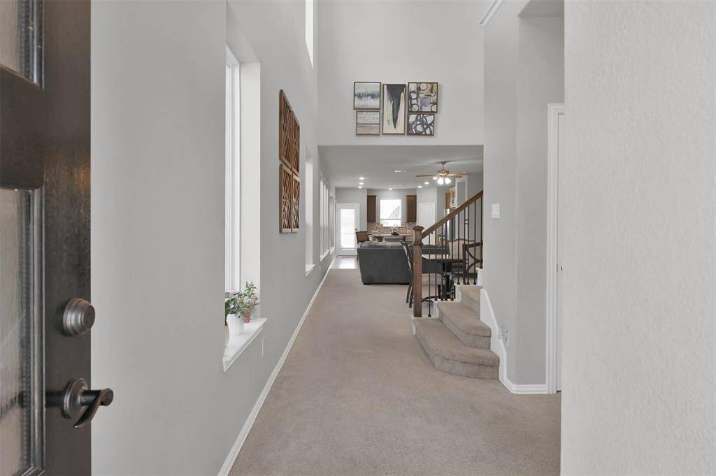 Bright, open entryway leading to a spacious living area with high ceilings, providing a welcoming and expansive feel