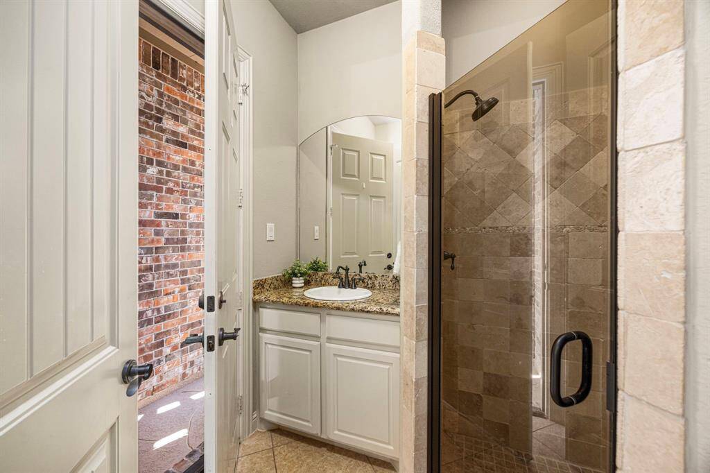This pool Bath features a convenient door leading to the backyard, making it perfect for outdoor entertaining. It includes a spacious shower with oil-rubbed bronze fixtures, a glass door, granite countertops, and elegant finishes for both style and functionality.
