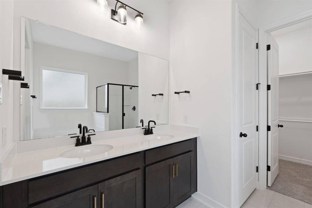 The en-suite bathroom offers a spa-like atmosphere with its elegant design, high end finishes, and tasteful lighting, creating a retreat within your own home.