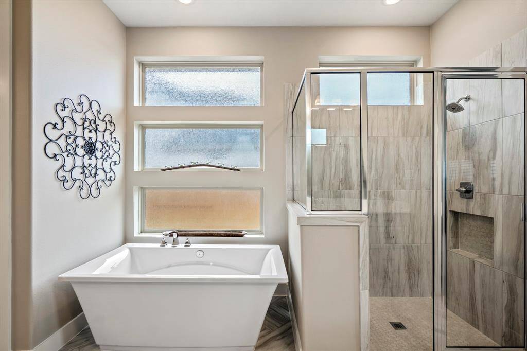Experience luxury in this primary bathroom, complete with a stunning freestanding tub, walk-in shower, sleek quartz countertops, and contemporary tile accents — the perfect oasis for relaxation and rejuvenation.