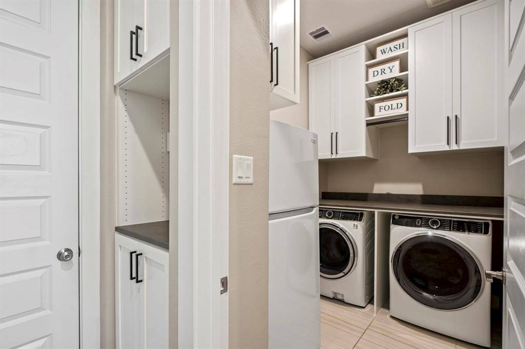 Step into a spacious laundry room with custom-built cabinets, shelves, and folding table, offering plenty of storage, plus additional space for a refrigerator!