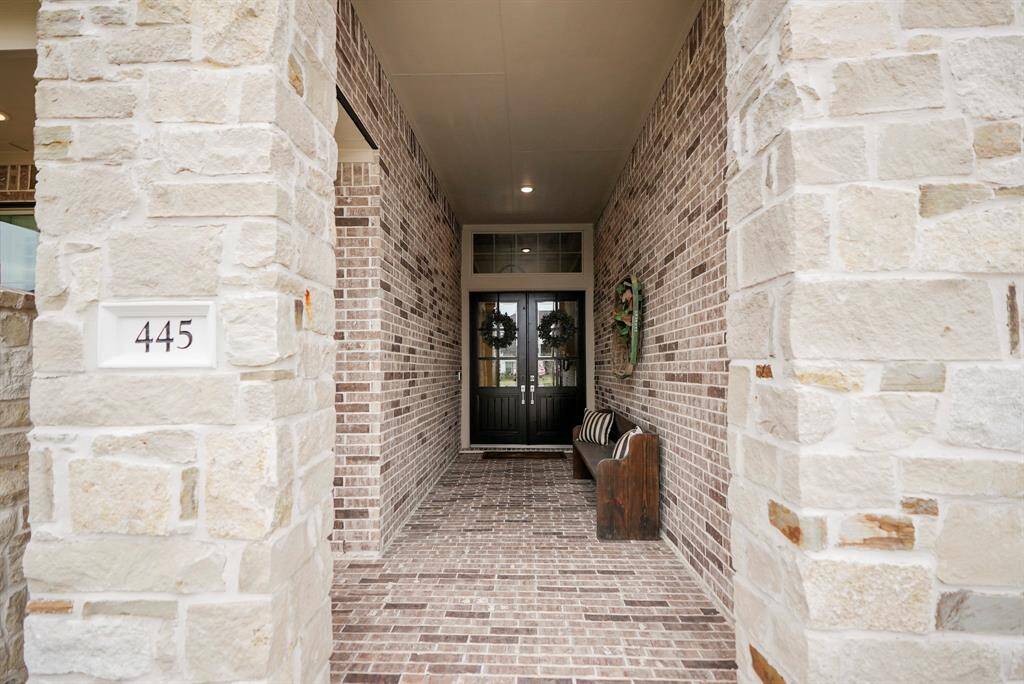 As you approach the front door, you are greeted by a stunning brick and stone elevation and a spacious front porch—perfect for welcoming guests! The grand 8-foot double-door entry, complete with keyless access and elegant recessed lighting, sets the tone for the luxury within.