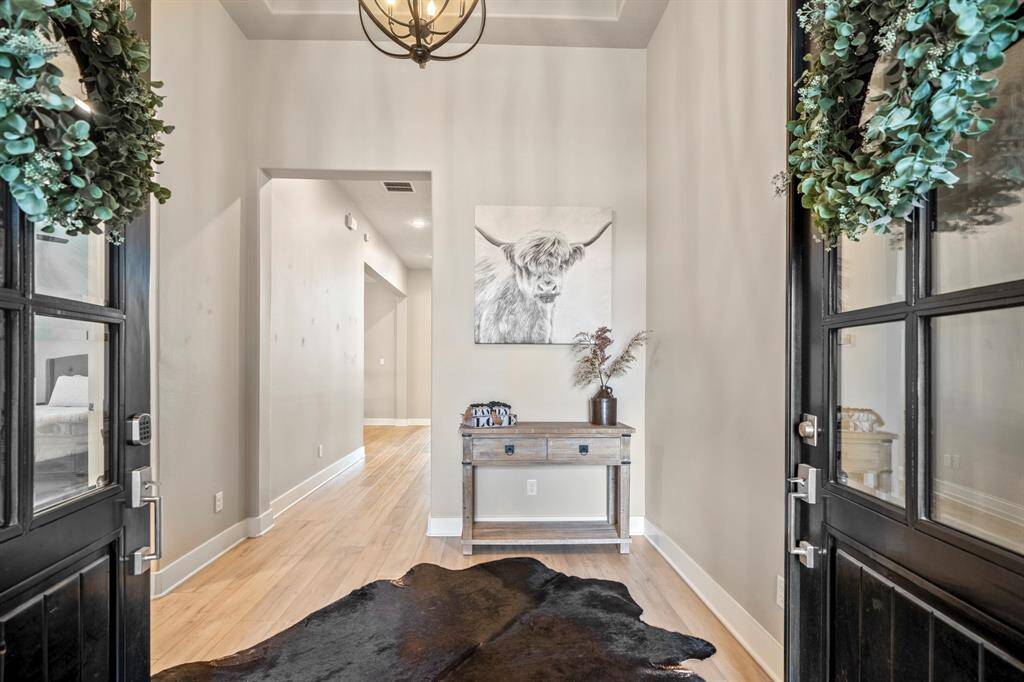 Stepping through the grand double doors, you're welcomed into an elegant entryway with stunning wood-look flooring that extends throughout the main living areas making it easy and clean to maintain. The high trace ceilings and natural light create a warm, welcoming atmosphere, setting the tone for the rest of the home.