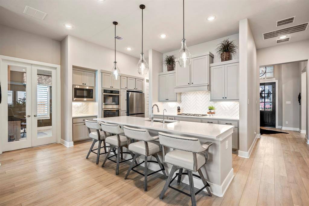 The heart of the home! This stunning chef’s kitchen features elegant cabinetry, a spacious island with seating, sleek stainless steel appliances, and stylish pendant lighting—perfect for gathering and entertaining.