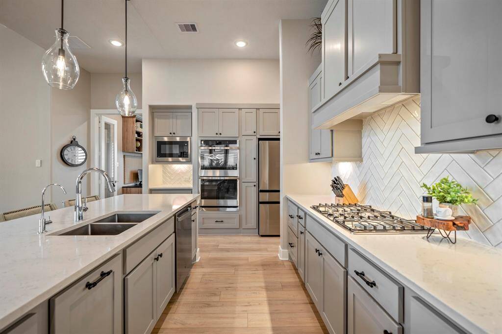 You will love the details of this kitchen! It features a reverse osmosis system, black cabinet hardware, double ovens, textured tiled backsplash, sleek painted cabinets, and quartz countertops.