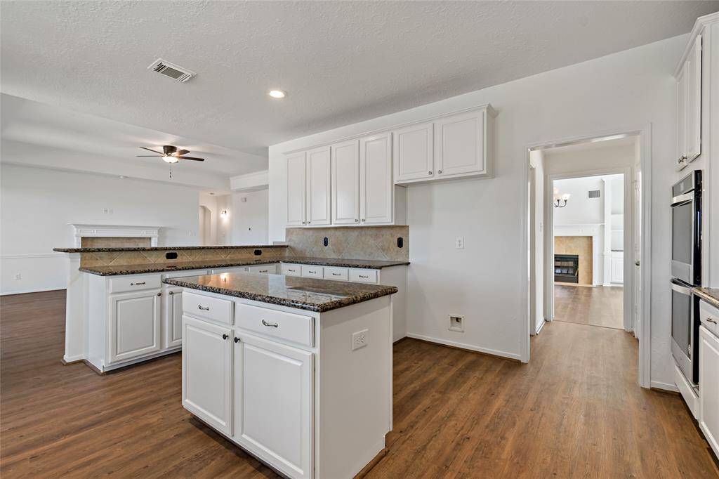 This inviting island kitchen boasts elegant granite countertops.