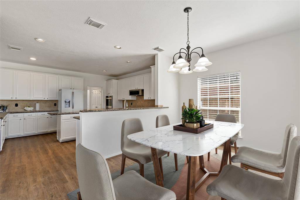 Bright and inviting, this breakfast room and kitchen feature sleek white cabinetry, modern appliances, and an elegant dining area perfect for gatherings.