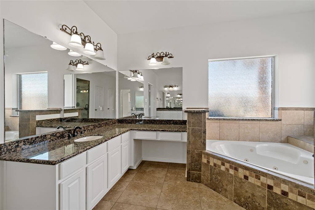 Luxurious primary bath featuring dual vanities, a spacious corner tub, and a separate shower.