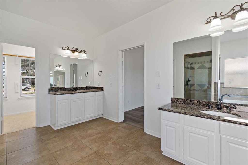 Spacious primary bath featuring elegant dual vanities and a generously sized closet.