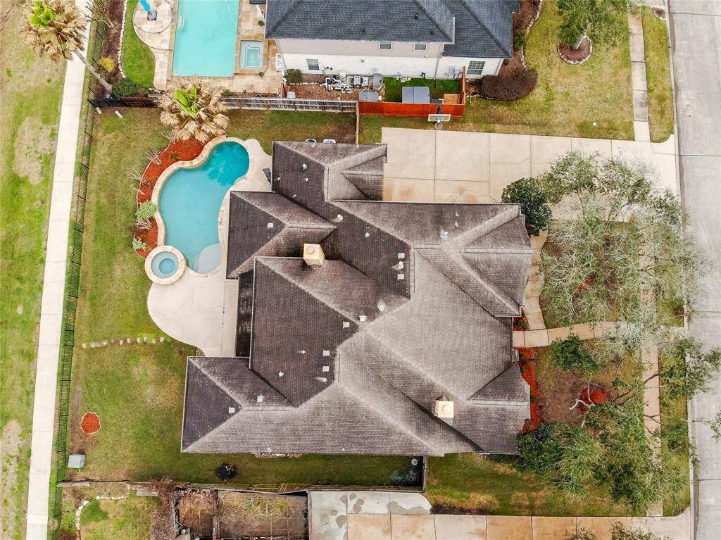 Discover your dream home with this stunning aerial view, showcasing a spacious property featuring a refreshing pool, expansive driveway, and lush landscaping. Perfect for relaxation and entertaining.