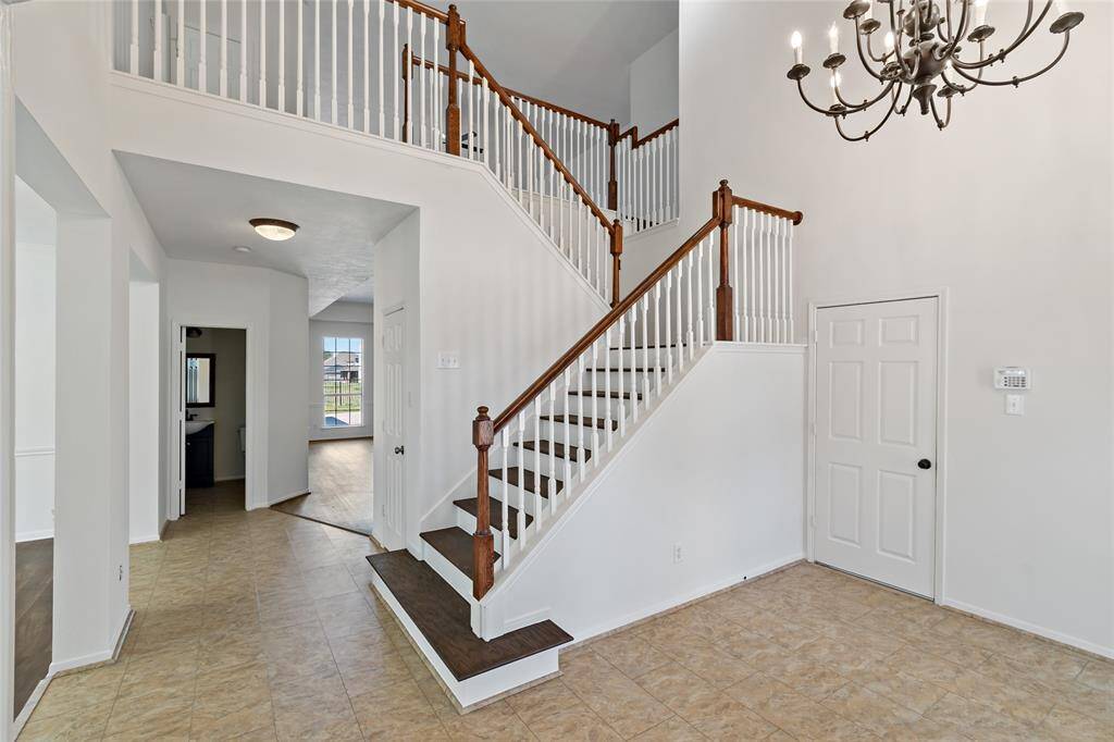 Welcome to a stunning entryway featuring a soaring ceiling, elegant chandelier, and a beautifully crafted staircase that sets the tone for this exquisite home.