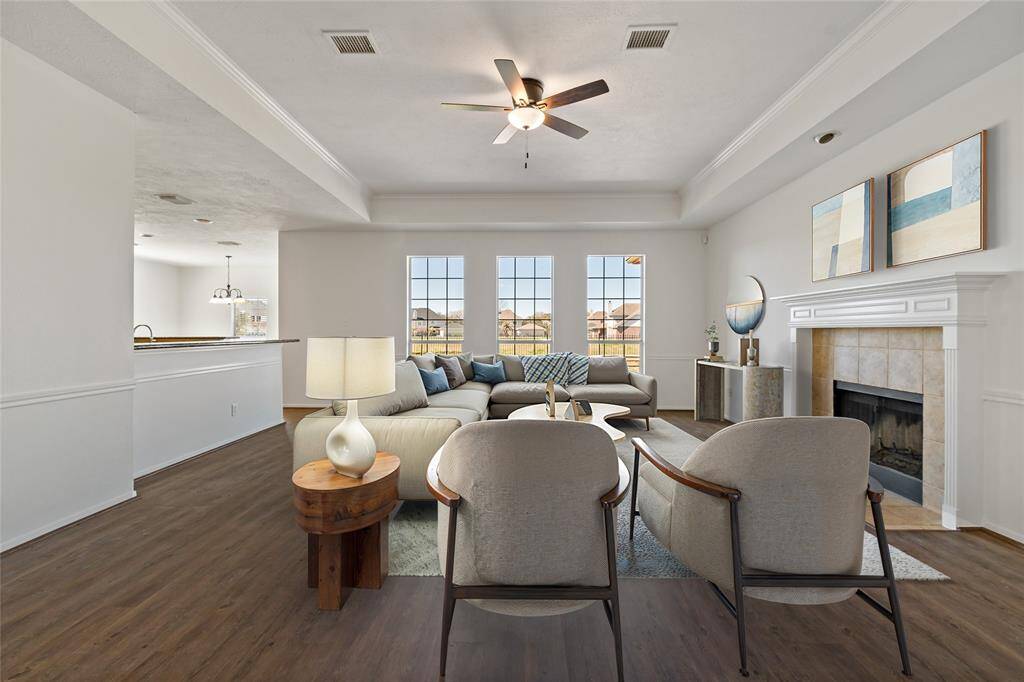Spacious and inviting family room featuring abundant natural light, a cozy fireplace, and elegant hardwood floors, perfect for relaxation and gatherings.