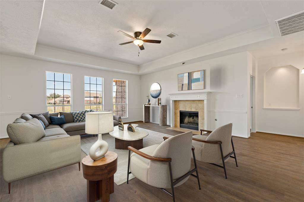 Spacious family room with abundant natural light, cozy fireplace, and elegant wood flooring—perfect for gatherings and relaxation.