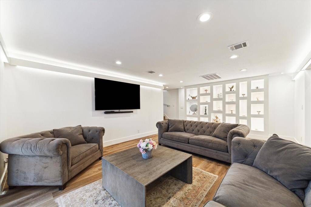The spacious den showcases LVP flooring, ambient lighting, and elegant backlit shelving, providing the perfect space to display your favorite collectibles.