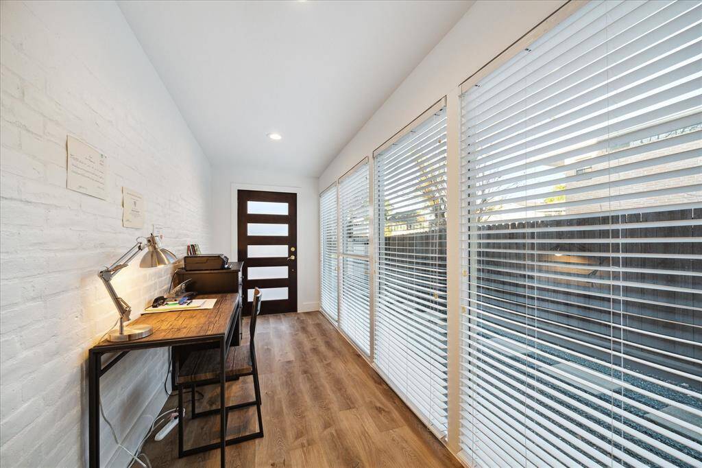 A separate entrance provides access to the study with LVP flooring and a wall of glass on one side with a brick accent wall on the other.