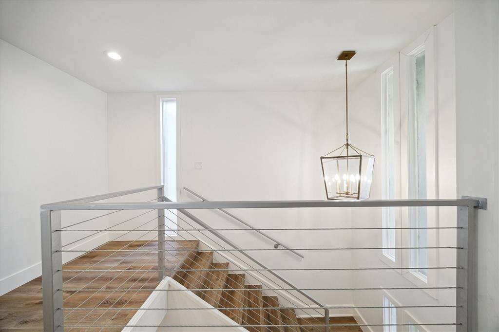 This open landing showcases modern railings and balusters, stylish lighting, and oversized windows that flood the space with natural light.