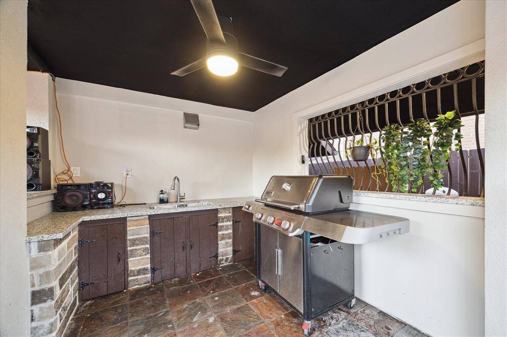 The covered summer kitchen offers a granite countertop, convenient sink, and ample space for your grill.