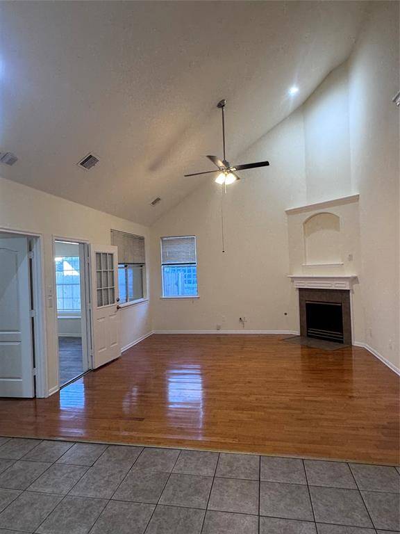High ceiling living room with fan and fireplace
