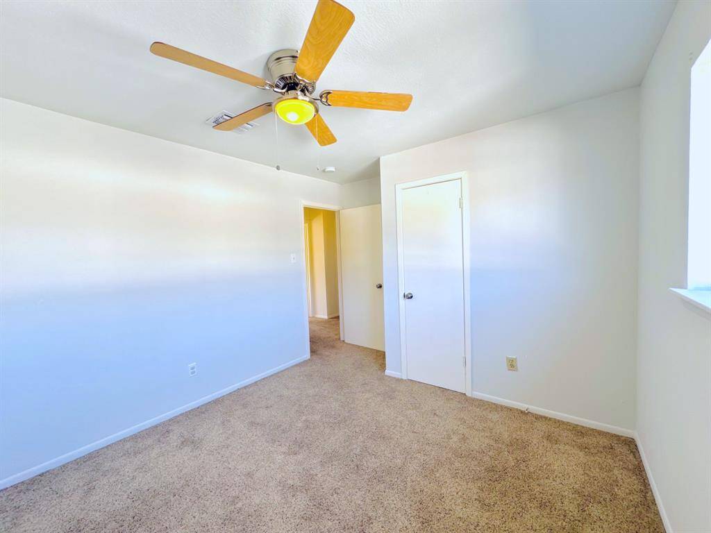 A bright bedroom featuring a ceiling fan for enhanced airflow and large windows for beautiful natural lighting.