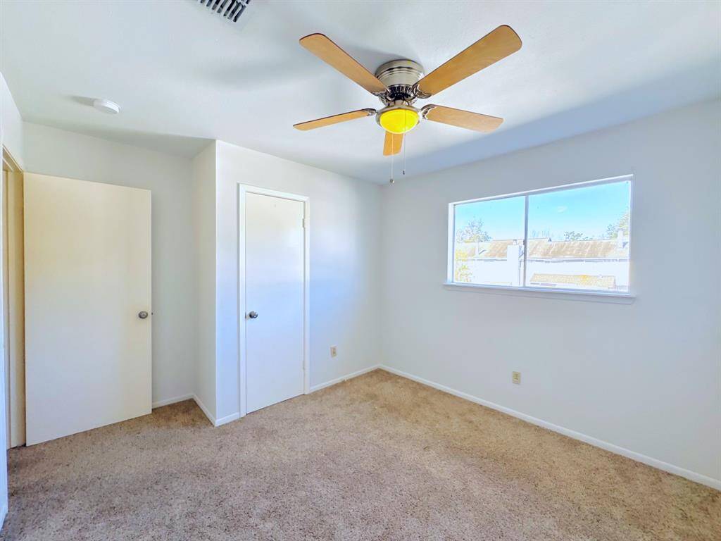 A second angle of the spacious bedroom, showcasing great natural light and a fan for year-round comfort.
