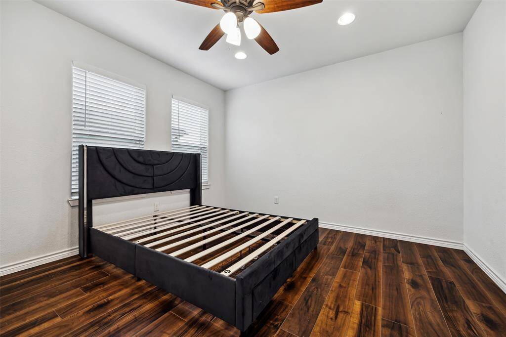 The primary bedroom is bright and spacious with a ceiling fan and two windows.