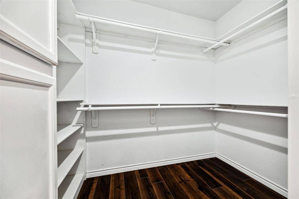 This photo shows the spacious primary walk-in closet with ample hanging space and shelving, featuring clean white walls. Ideal for organized storage.