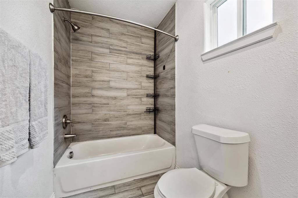 The primary bathroom features a tub-shower combo with stylish wood-look tile walls and a curved shower rod.
