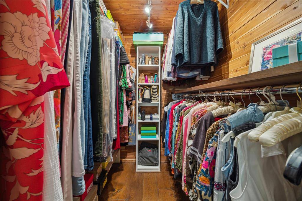 This photo showcases a spacious walk-in closet with wooden walls and ample hanging space. It features additional shelving for accessories, creating an organized and functional storage area.