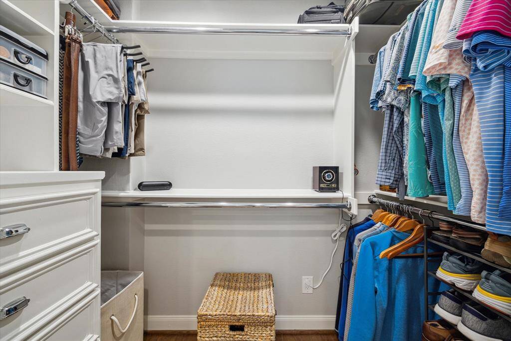 This is a well-organized walk-in closet featuring ample hanging space, drawers, and shelves. It has a neat arrangement of clothes, shoes, and accessories, offering efficient storage solutions.