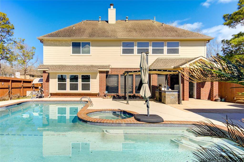 Pool with spa surrounded by bar & grill. Outdoor fireplace