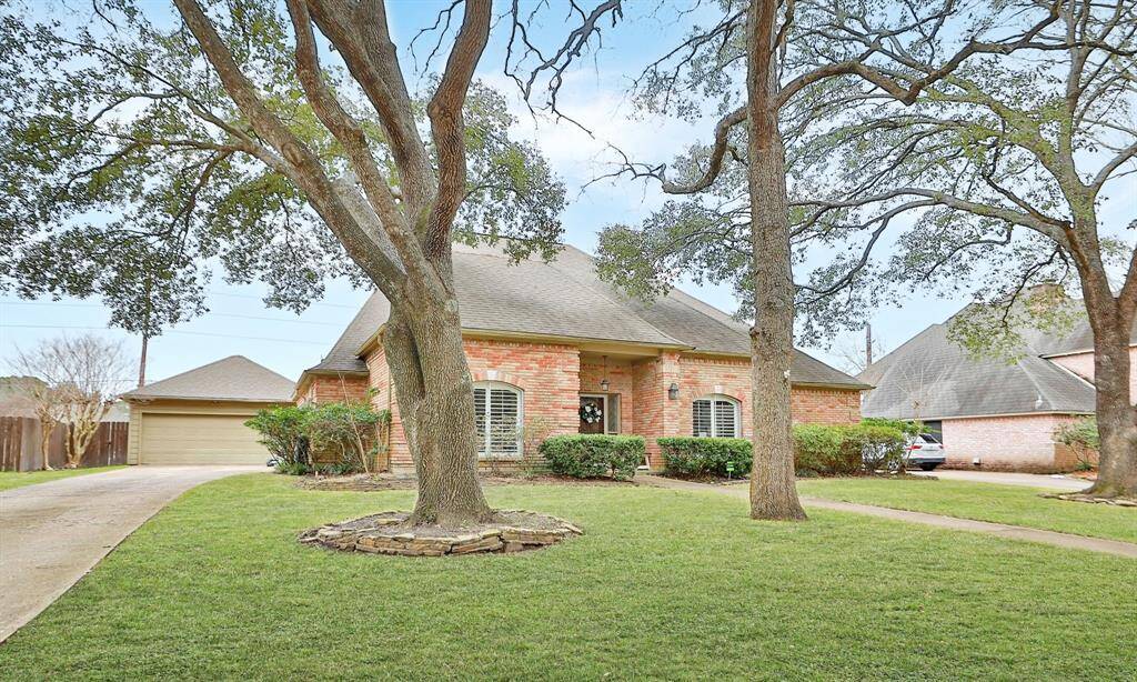 Charming brick home with a classic design, nestled among mature trees. It features a well-maintained front lawn, a long driveway leading to a detached garage, and welcoming curb appeal. Perfect for those seeking a serene suburban setting.