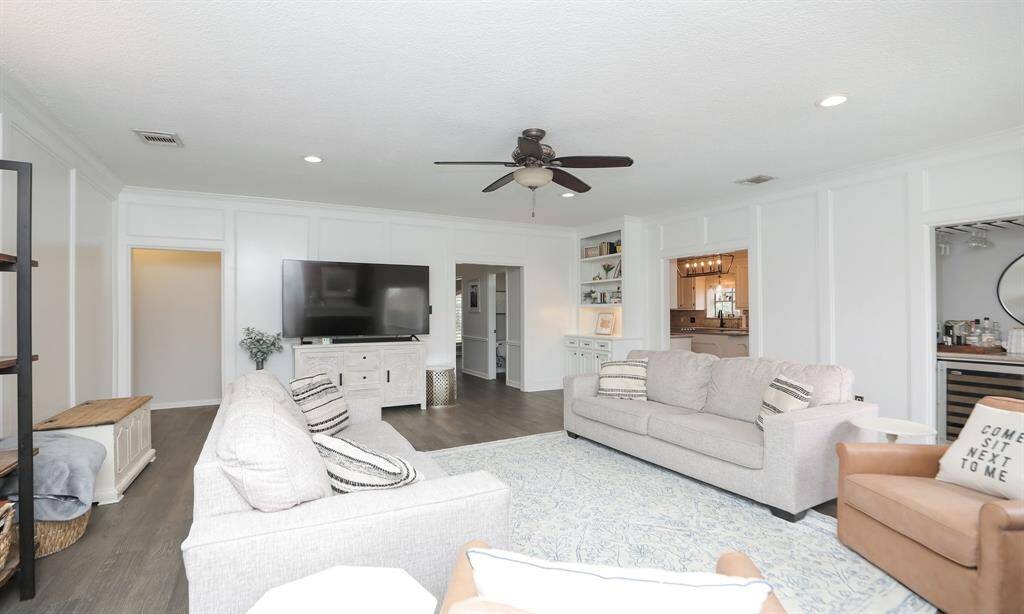The den has light walls with elegant paneling, and recessed lighting.