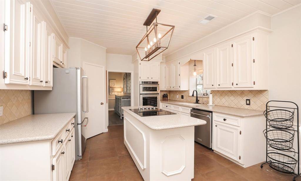 The kitchen features elegant white cabinetry, a wall oven, and a built-in dishwasher.