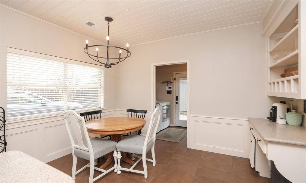 the breakfast room includes a modern chandelier, a large window, wainscoting, and built-in desk with shelving.