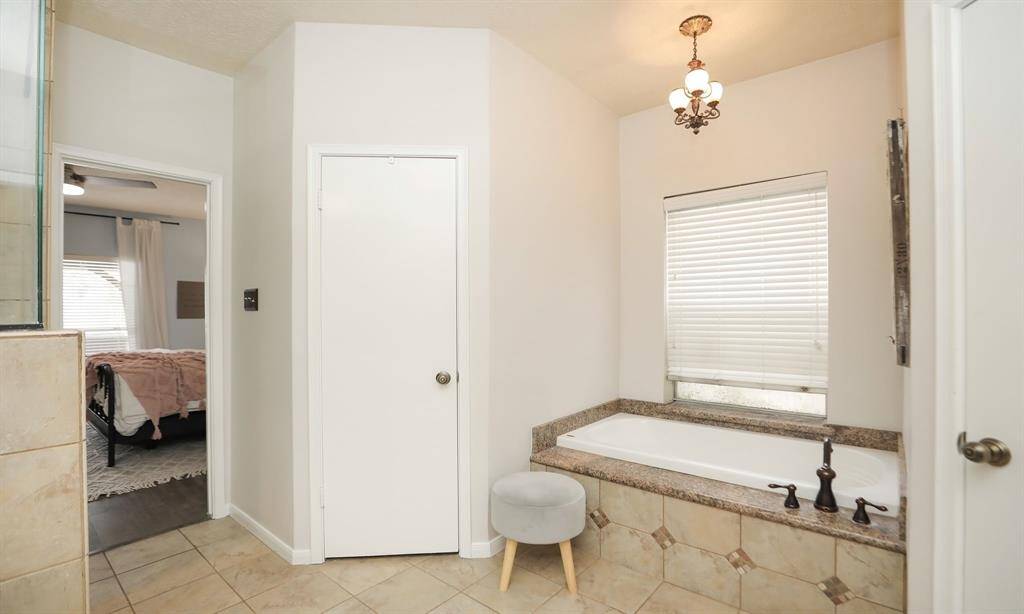 The primary bathroom has a built-in bathtub, tiled flooring, and stylish light fixtures.