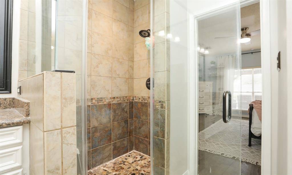 The bathroom also includes a glass-enclosed shower featuring stone and tile design.