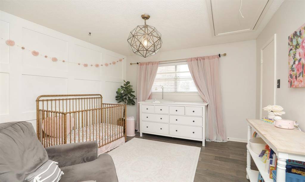 This charming upstairs bedroom is decorated with soft accents and a modern geometric light fixture.
