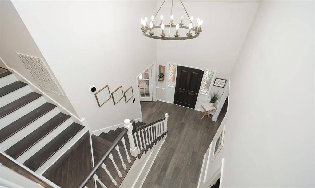 A stunning entryway with high ceilings and a grand staircase with a stylish chandelier.
