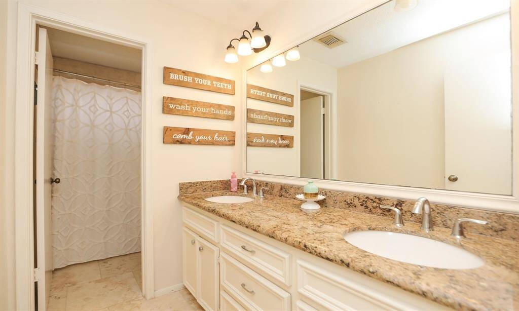 The upstairs bathroom features a double sink vanity with granite countertops, a large mirror, and stylish light fixtures. The space has a separate shower area.