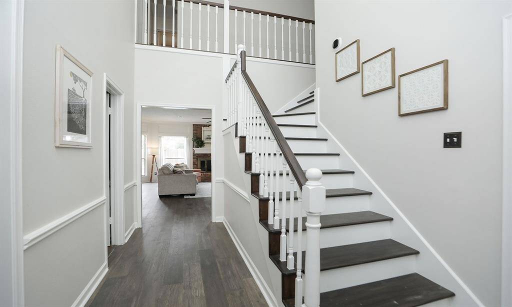 The foyer showcases a bright, inviting entryway with a modern staircase featuring dark wood steps and white railings.