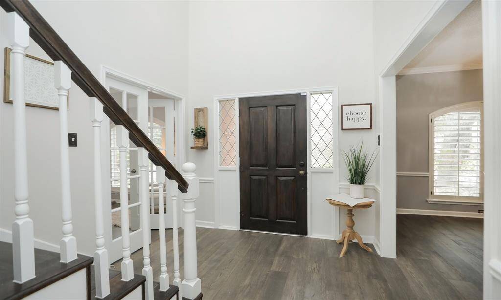 This inviting entryway features a dark wooden front door with decorative glass sidelights.