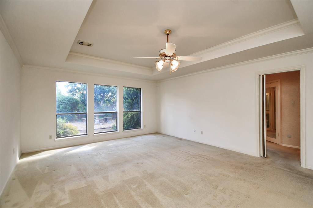 Owner's suite with tray ceiling overlooks patio and pool.