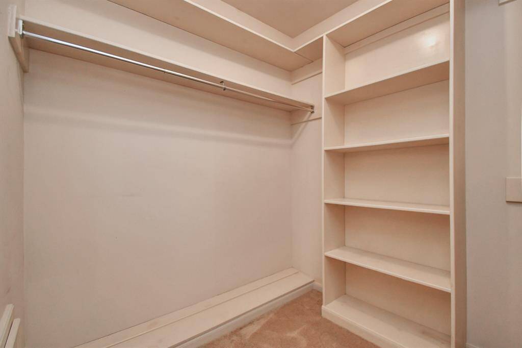 A view of one side of one walk-in primary closet.