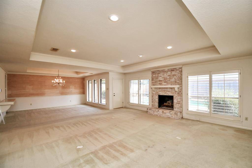 View from living toward dining with access to covered rear patio. Classically elegant touches such as plantation shutters and grass cloth wallpaper in dining add sophistication to this custom plan. Vintage chandelier in dining room is excluded.