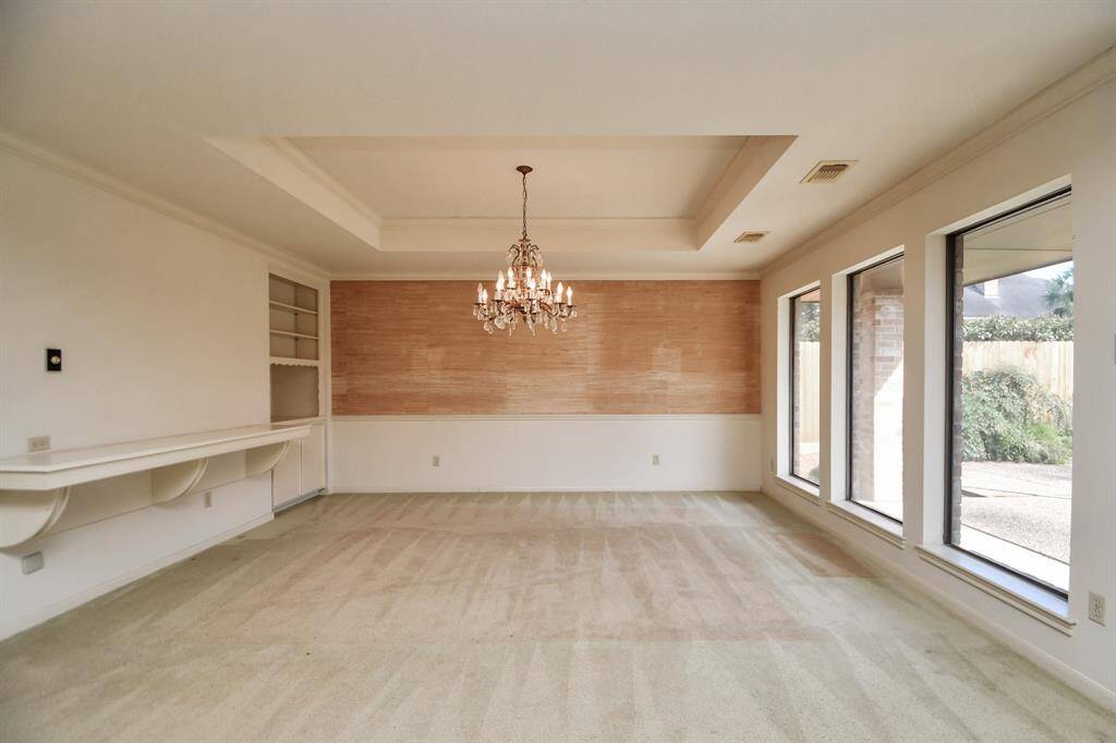 Elegant dining room with tray ceiling overlooking the backyard. Vintage chandelier is excluded from sale.