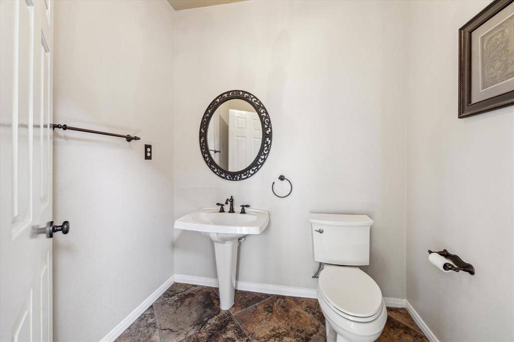 This powder room is conveniently located off the foyer and features a pedestal sink, tile flooring and beautiful wall mirror.