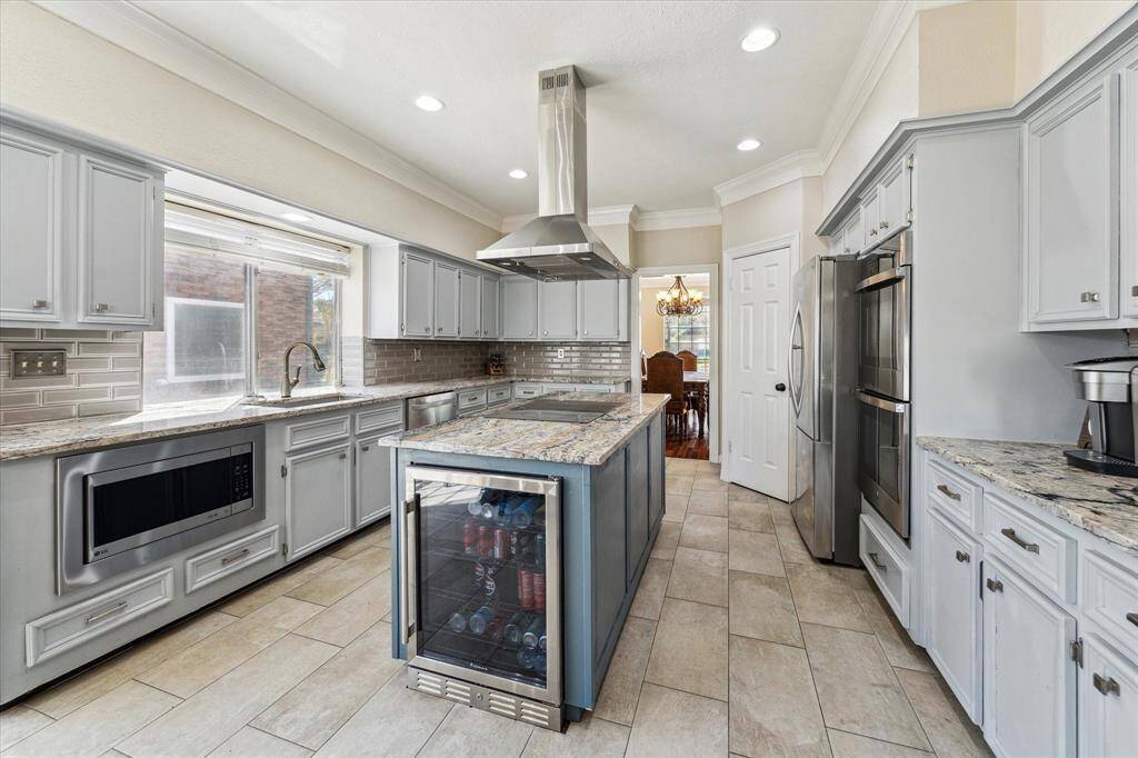 This beautifully updated kitchen remodeled in 2022 boasts sleek level 6 granite countertops, stainless steel appliances, including a double oven for effortless cooking and built in microwave. The large island with a built-in beverage fridge adds both style and convenience, while the modern vent hood and subway tile backsplash complete the sophisticated look