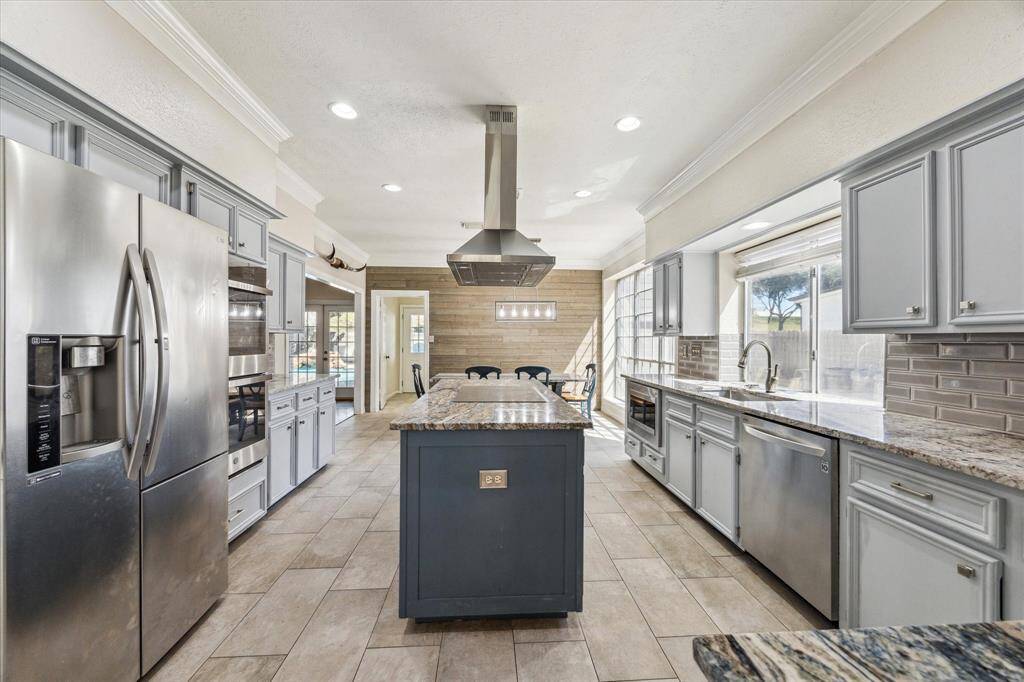 In addition to much natural light, this kitchen, is equipped with recessed lighting, elegant crown molding, and ample cabinet space. The stainless steel refrigerator remains with the home.