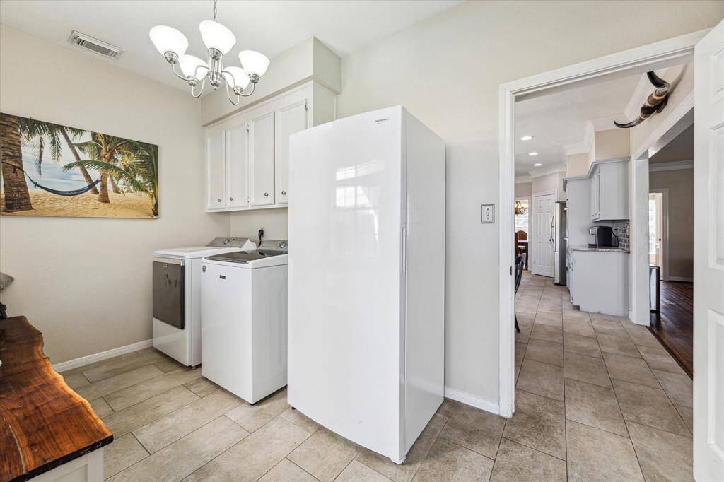 Conveniently located just off the kitchen, this spacious utility room offers easy access to the backyard. Featuring ample cabinet storage, washer/dryer connections, and space for an additional refrigerator or freezer, this room is designed for efficiency. A standout feature is the built-in custom Black Walnut storage bench.